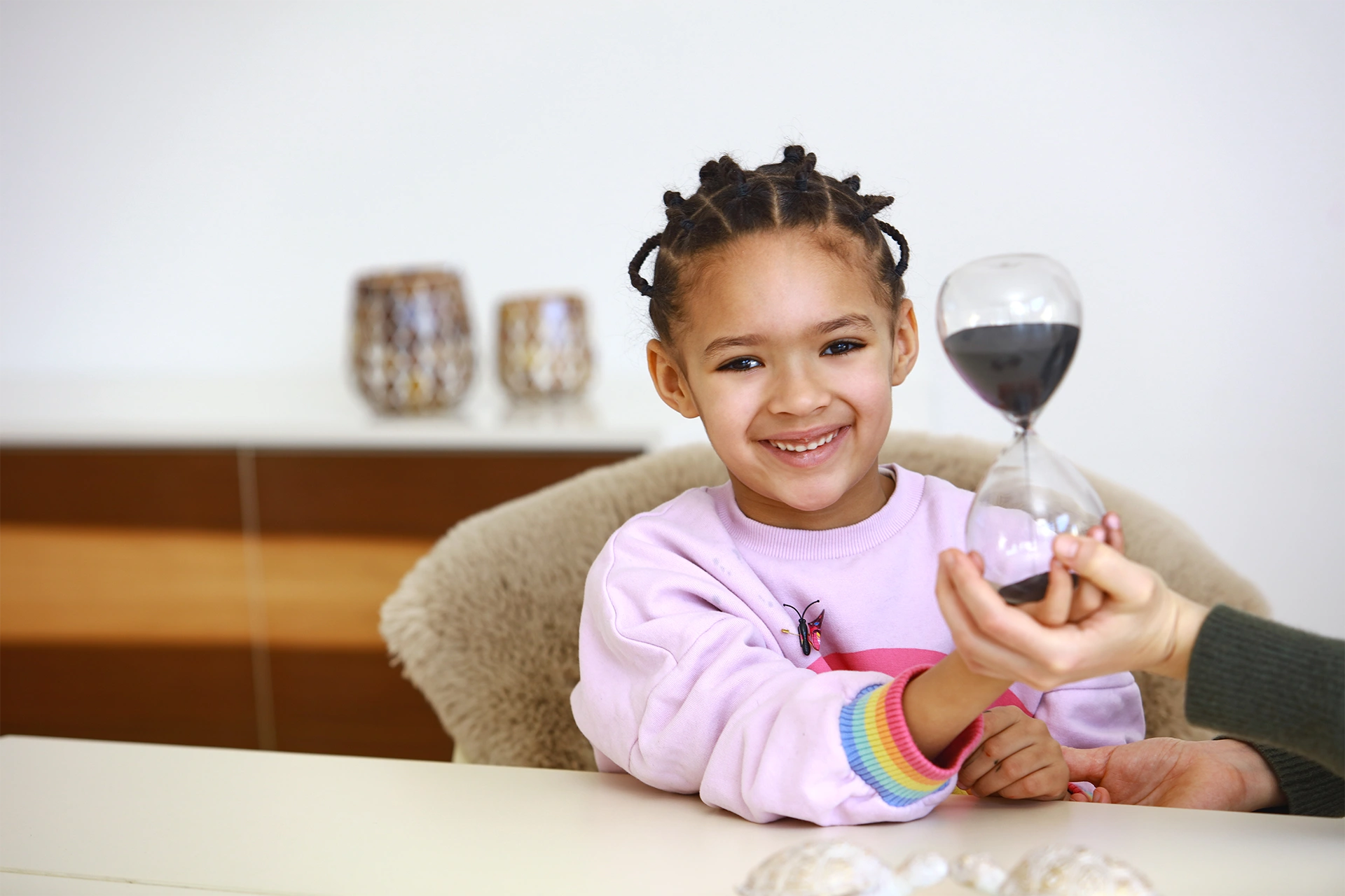 Therapeutische Übung mit Kind und Sanduhr zur Veranschaulichung von Emotionen während einer Familientherapie systemisch im Heilpraktiker Quartier.